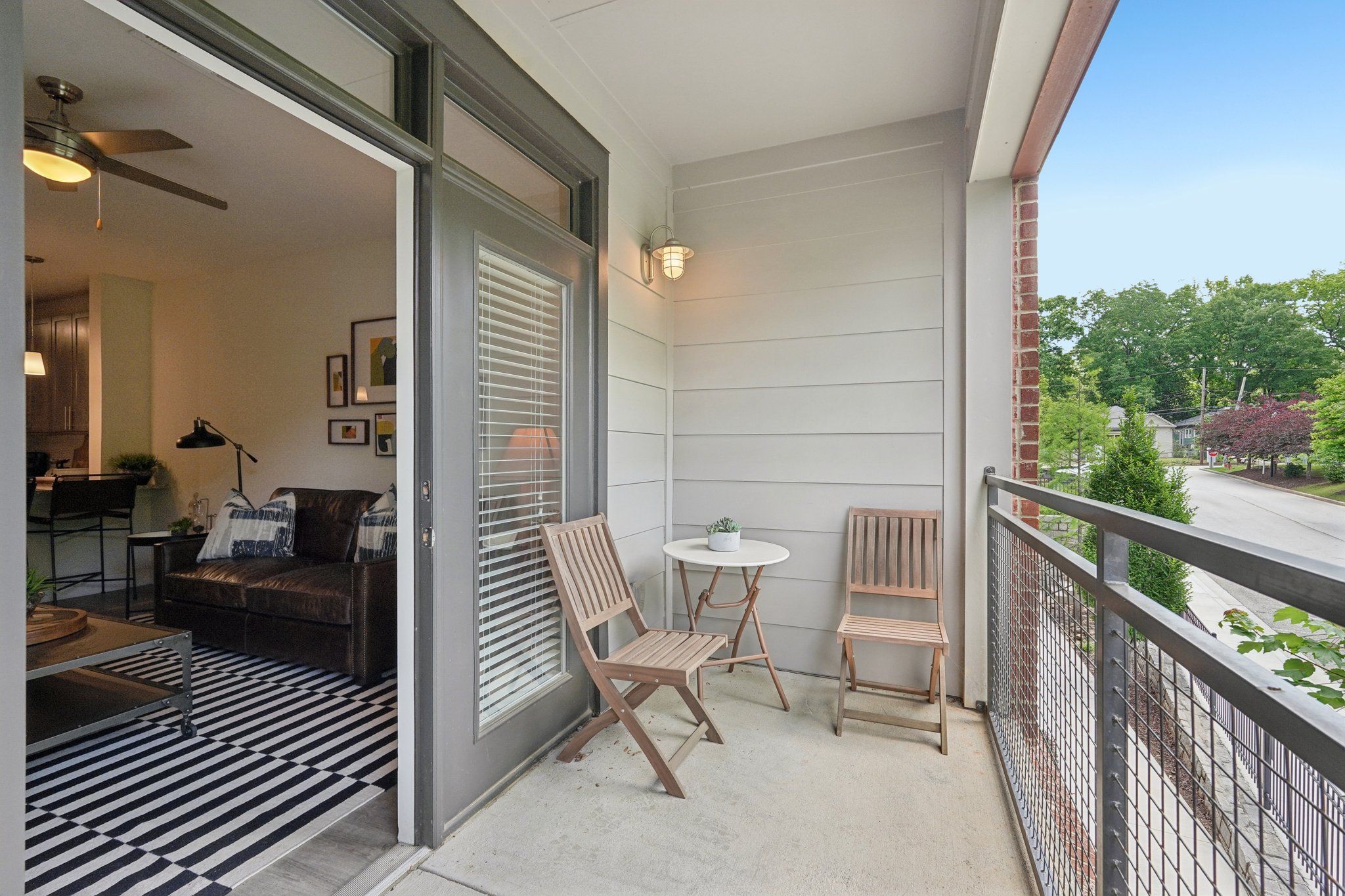 A private balcony at The Kirkwood Apartments at Edgewood overlooking a quiet street with lush green trees.
